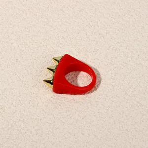 Red acrylic spike ring detail, edgy punk gold cone studs detail shot for women fashion jewelry.
