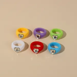 Detailed shot of colorful acrylic resin rings with sparkly heart-shaped crystal rhinestones.