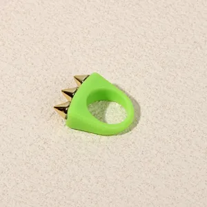 Detail view of a stylish neon green acrylic resin ring featuring three striking gold metal spike studs.