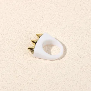 White acrylic ring detail featuring three gold metal spikes for a bold punk rock fashion look.