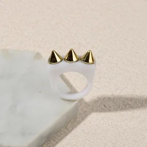 White acrylic ring with three gold spikes, stylish punk fashion jewelry detail.
