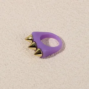 Close-up of a stylish purple acrylic ring featuring bold gold metallic spikes for a punk look.
