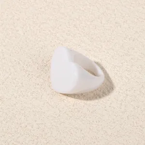 Close-up of a minimalist white acrylic heart ring, showing smooth texture and shape detail.