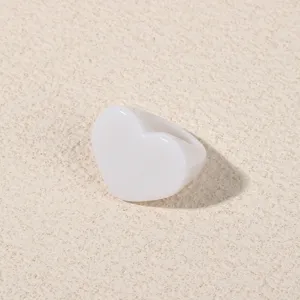 Minimalist white acrylic heart ring detail shot, smooth resin texture fashion jewelry.