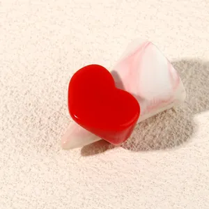 Close-up of a bold red heart acrylic ring on a chic display cone, perfect minimalist fashion detail.