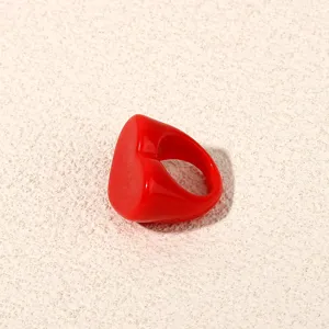 Close-up detail shot of a bright red chunky acrylic heart ring, showing glossy surface.