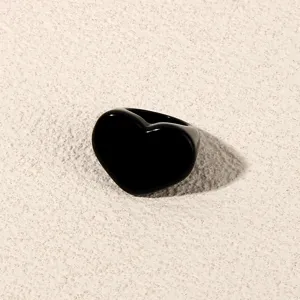 Black acrylic heart ring detail shot, minimalist geometric fashion jewelry for women.