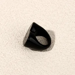 Detailed close-up of a minimalist black acrylic ring, glossy chunky fashion jewelry piece.