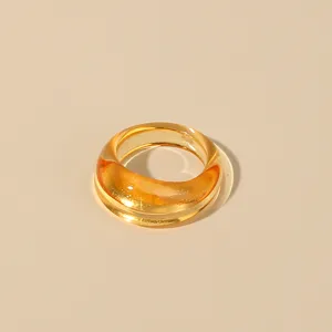 Amber acrylic chunky ring close-up, minimalist transparent resin finger jewelry detail view.