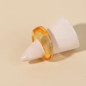 Amber resin ring detail showing transparent glossy surface and minimalist geometric round shape.