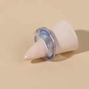 Detailed close-up of a translucent blue acrylic resin ring on a pink display cone, minimal.