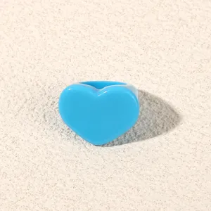 Blue acrylic heart ring detail shot, minimalist fashion resin finger jewelry accessory.