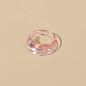 Close up view of minimalist pink transparent acrylic ring, showing smooth glossy resin finish.