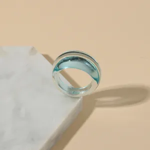 Close-up view of a minimalist transparent acrylic ring with light blue inner core.