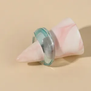 Detailed shot of a minimalist translucent light blue acrylic ring on a marbled cone display stand.