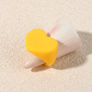 Close-up detail shot of bright yellow heart acrylic ring on marble display cone.