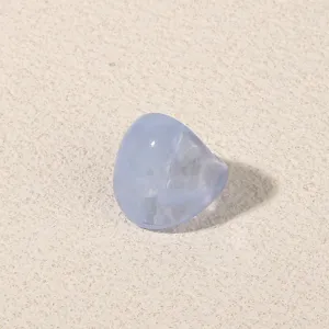 Detail view of a light blue translucent acrylic geometric ring on textured background.