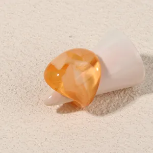 Detailed close-up view of a stylish amber acrylic ring featuring a simple geometric design.