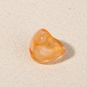 Close-up detail shot of trendy orange acrylic geometric ring showing glossy resin texture.