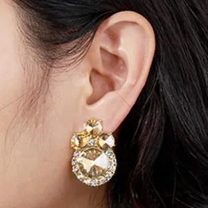 Close-up detail shot of exquisite crystal flower stud earrings featuring sparkling yellow and clear stones.