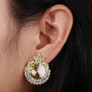 Close-up detail shot of exquisite gold-toned crystal stud earring with sparkling rhinestone halo.