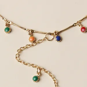 Goudkleurige metalen kettingdetails met kleurrijke ronde edelsteenbedels voor modieuze enkelsieraden.
