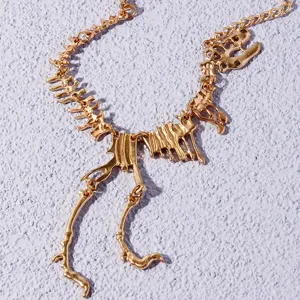 Gold dinosaur skeleton pendant necklace detail view showcasing unique animal bone design.
