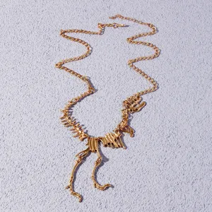 Detailed shot of the gold dinosaur skeleton necklace featuring intricate bones and fine chain links.