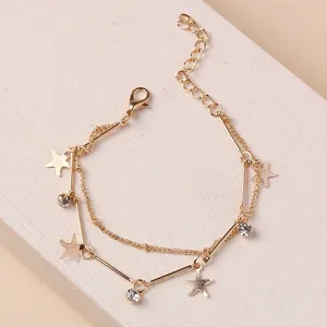 Dettaglio bracciale multistrato dorato, strass scintillanti e graziosi ciondoli stella.