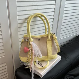 Bolso de lona y cuero amarillo y beige elegante bolso cruzado de hombro con bonito colgante.