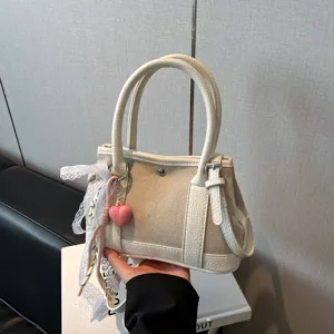 Vista detallada del bolso de hombro casual para mujer, bolso beige con colgante de corazón.