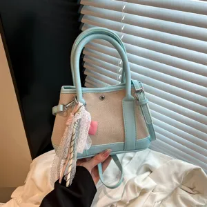 Primer plano de los detalles del bolso cruzado de lona y cuero con un bonito colgante de encaje.