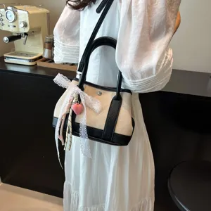 Elegante bolso de hombro de lona para mujer con lazo de encaje y colgante de corazón chic.