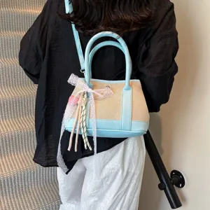 Vista detallada del bolso de cubo de paja para mujer con lazo de encaje y dijes elegantes.