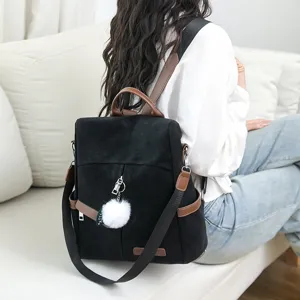 Sac à dos noir élégant avec détails marron et pompon duveteux, idéal pour les trajets quotidiens.
