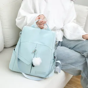Vue détaillée du sac à dos pour femme bleu clair avec pompon duveteux et lanières polyvalentes.