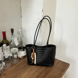 Μαύρη πλεχτή τσάντα tote λεπτομέρεια με λουρί ώμου, σχέδιο καλαθιού και διακοσμητικό κρεμαστό.