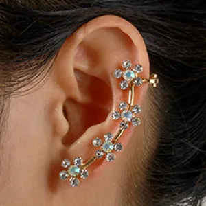 Close-up detailweergave van de goudkleurige bloemen oorring manchet met fonkelende strass steentjes.