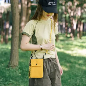 Vista dettagliata della mini borsa a tracolla gialla da cellulare indossata da una modella.