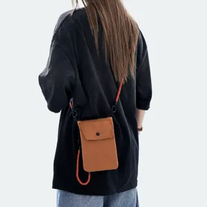 Vista dettagliata della mini borsa a tracolla marrone con cinturino rosso indossata.