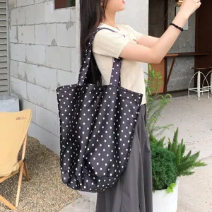 Λεπτομέρεια της μαύρης casual τσάντας tote με λευκές βούλες σε εξωτερικό περιβάλλον.