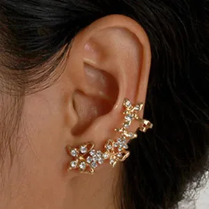 Gedetailleerde close-up van een gouden oormanchet met sprankelende strass-steentjes.