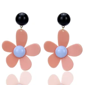 Detalle de pendientes de flores acrílicas, diseño floral rosa con toques negros.
