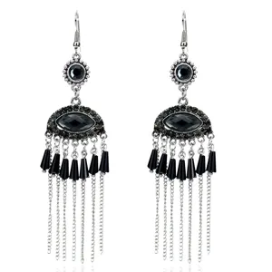 Vista detallada de pendientes de flecos metálicos estilo bohemio con colgante de mal de ojo.