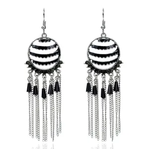 Detalle de los pendientes colgantes retro de metal con patrón en blanco y negro y cadenas.