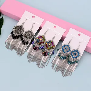 Primer plano de pendientes colgantes de metal geométrico con pedrería y diseño bohemio.