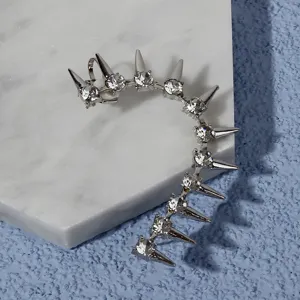 Gedetailleerde close-up van een punk zilveren oormanchet met stoere pinnen en heldere strass steentjes.