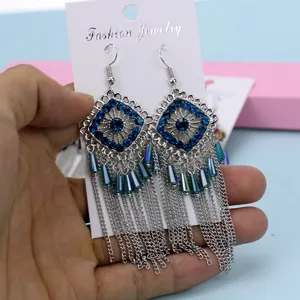 Detalle de pendientes de flecos de metal bohemio con diamantes de imitación azules y patrón.