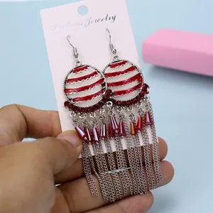 Pendientes de borla metálicos con pedrería roja y cadenas múltiples vista de detalle.