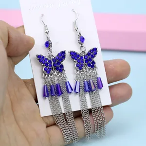 Gedetailleerde close-up van blauwe strass vlinder kwast oorbellen met fijne kettingen.